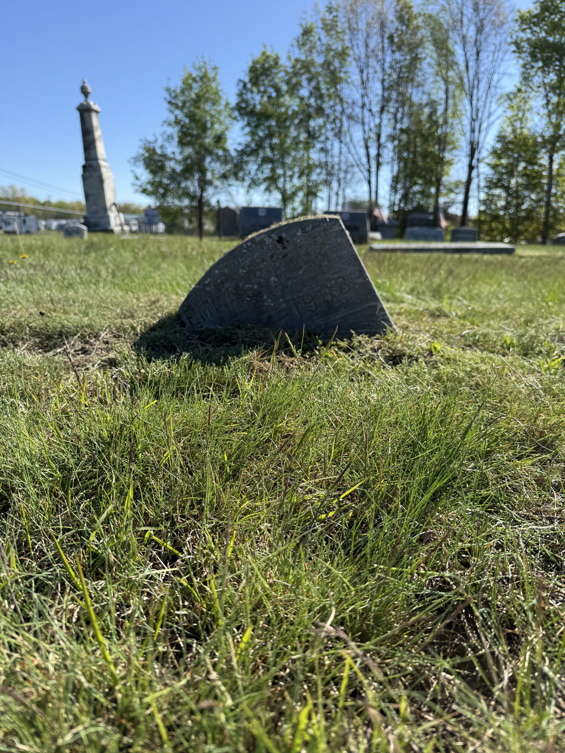 Sunken gravestone before leveling and reset work showing cemetery settlement problem