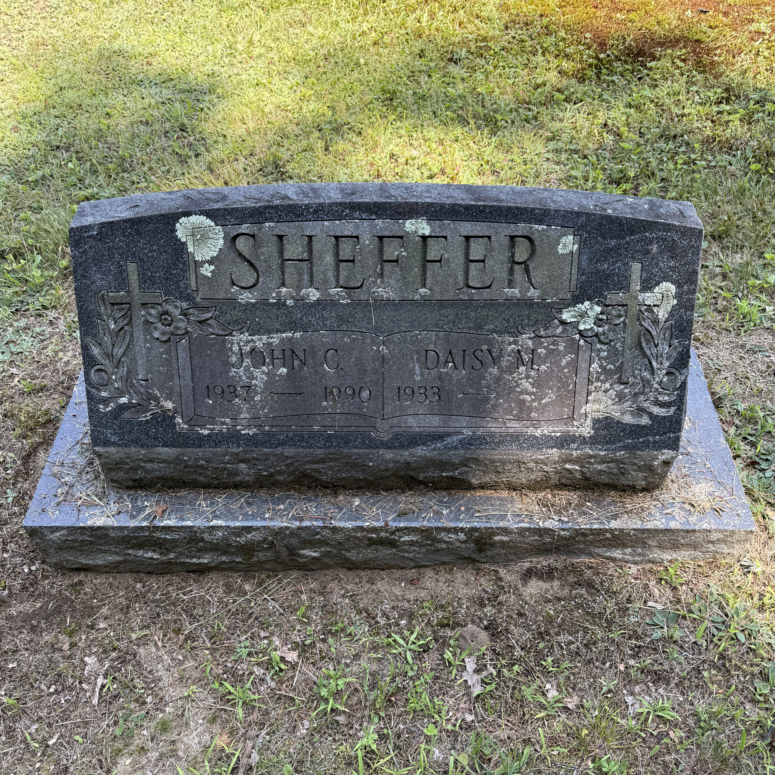 Lichen covered gravestone with biological staining and reduced readability