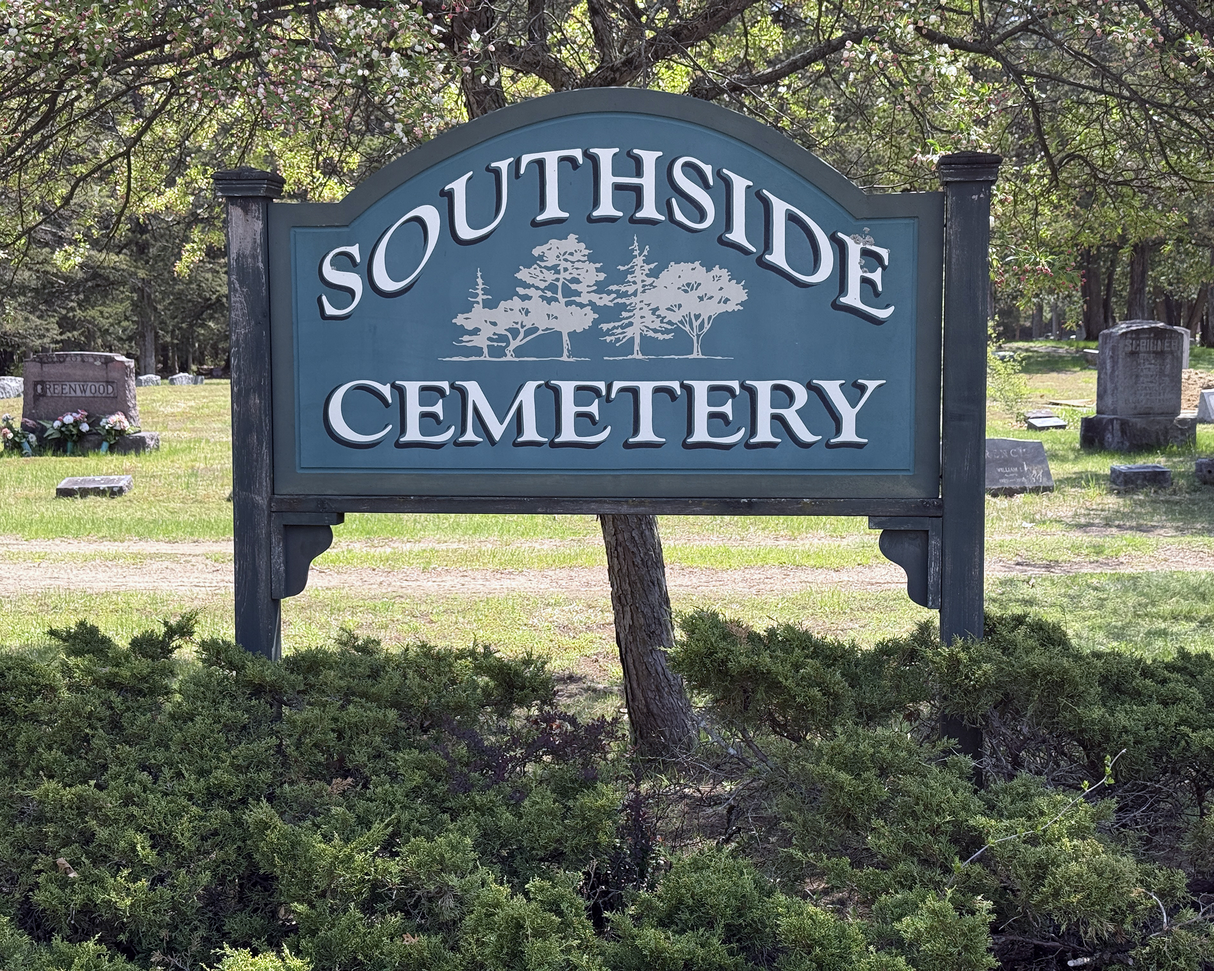 Southside Cemetery Entrance Sign with Shrubbery in foreground and Gravestones in the Background in South Glens Falls, New York.