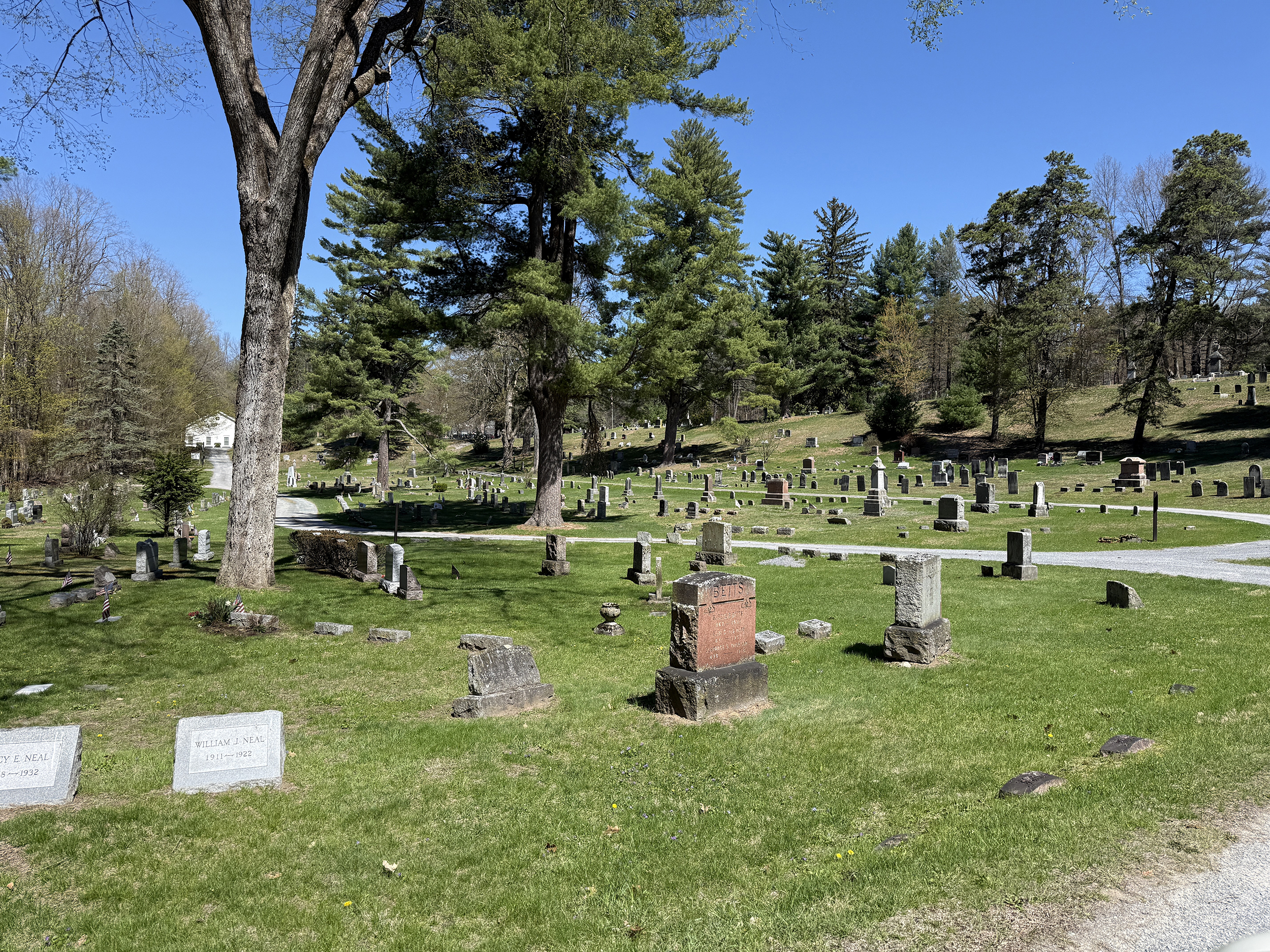 Roadway view through Jonesville Cemetery in Clifton Park New York with historic graves and wooded hills