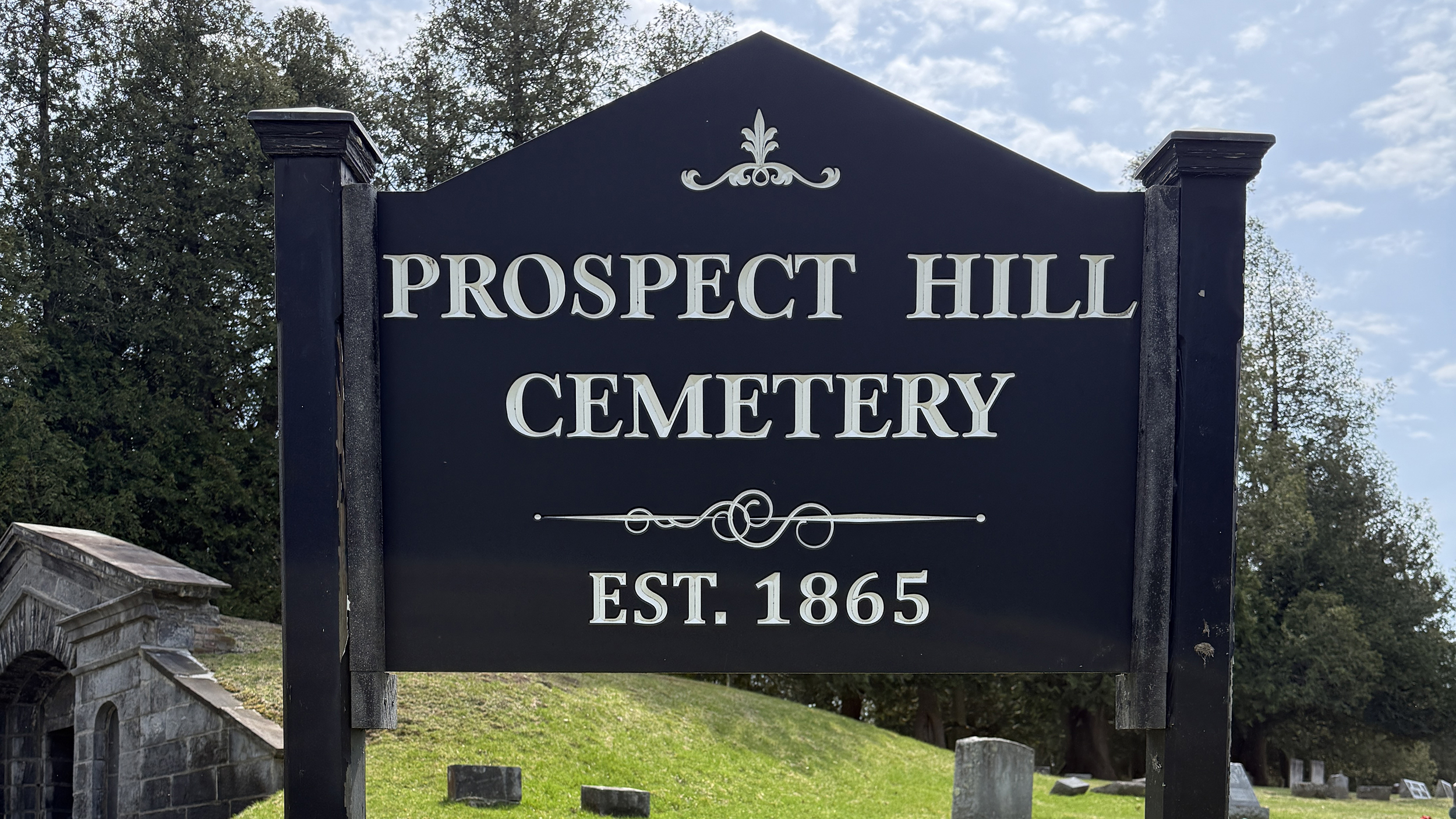 Prospect Hill Cemetery entrance sign in Schuylerville New York with cemetery grounds and hillside behind it