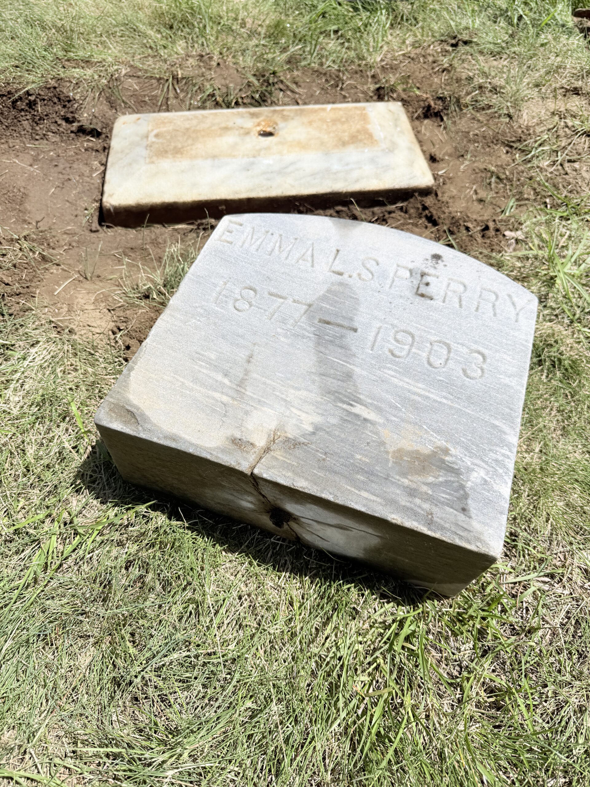 Gravestone repair and leveling work in progress during excavation and reset