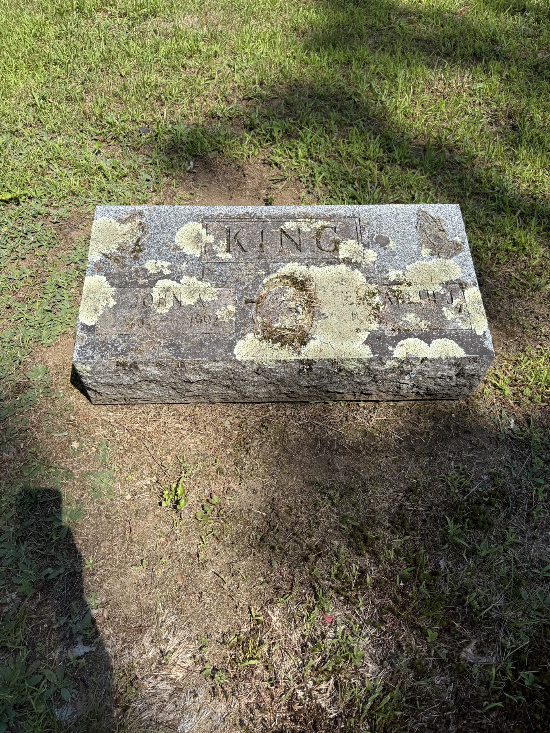 Severe biological growth on a headstone showing why individual memorial care may still be needed