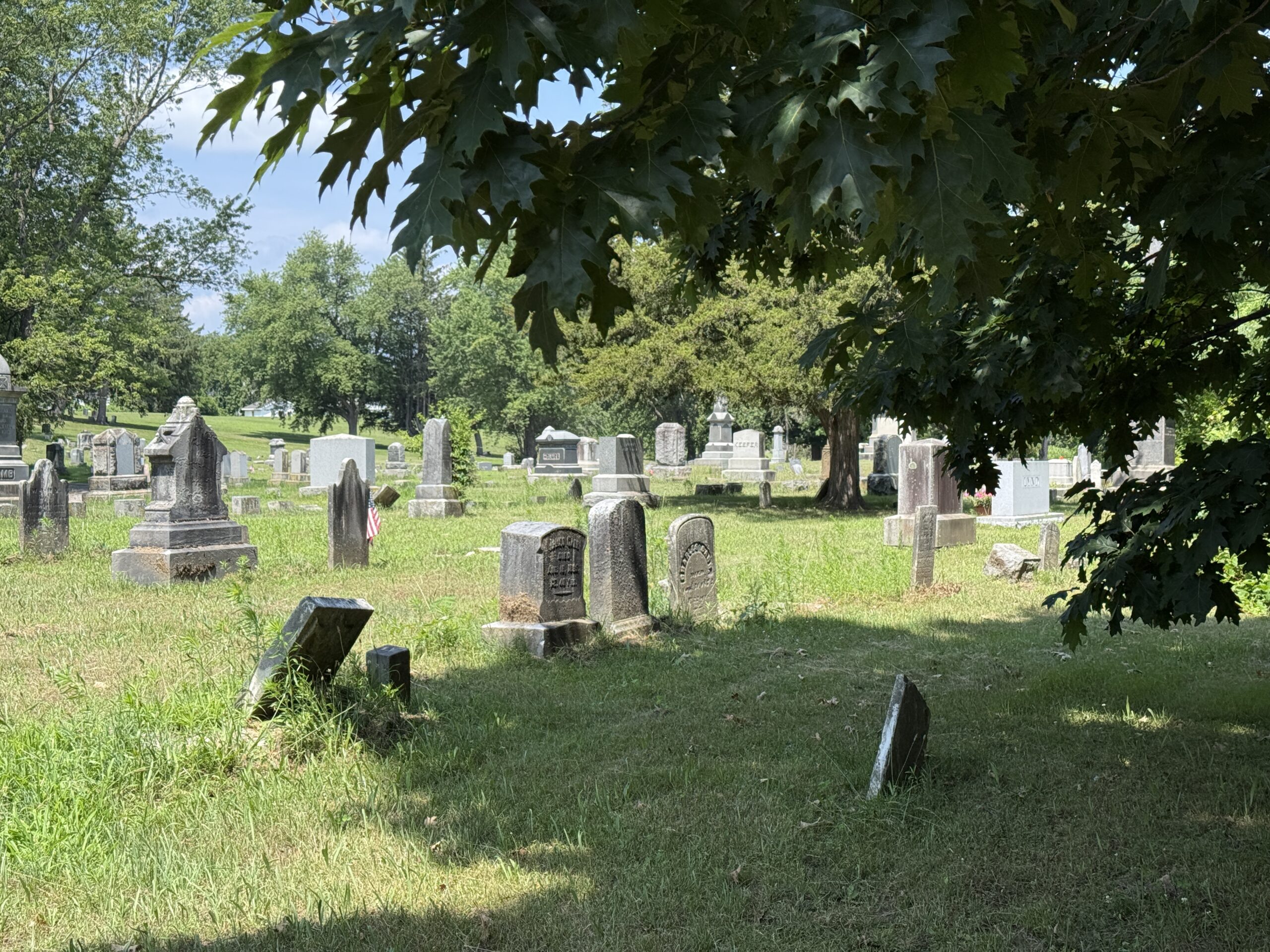 Historic headstones and family monuments beneath mature trees at Hudson View Cemetery in Mechanicville New York